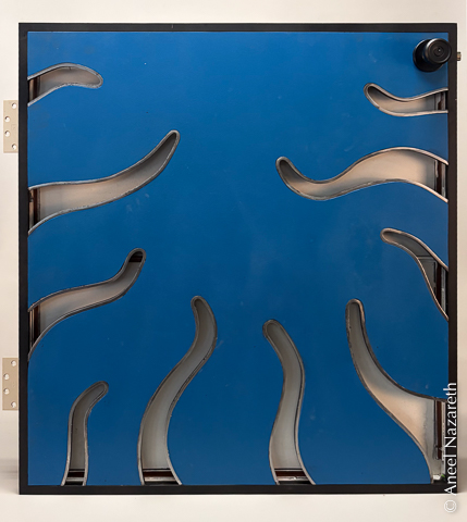 The assembled door with hinges and doorknob installed. The black frame sets off the shining silver of the tentacles and the blue of the sheet.